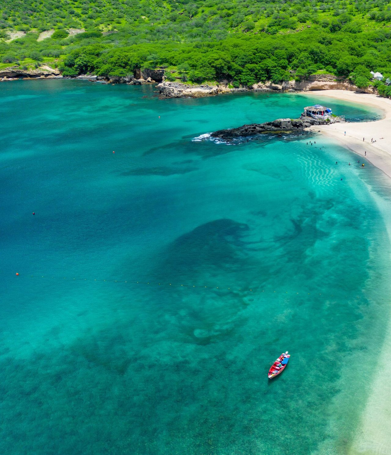 Playa paradisíaca con aguas cristalinas de color turquesa y arena blanca, con barcos coloridos anclados en la orilla