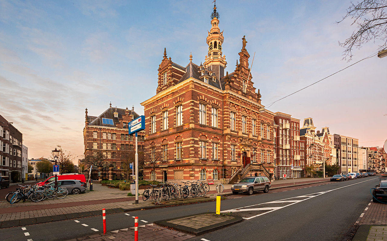 Vista exterior de Pestana Amsterdam Riverside, con ladrillos rojos, bicicletas estacionadas y cielo claro