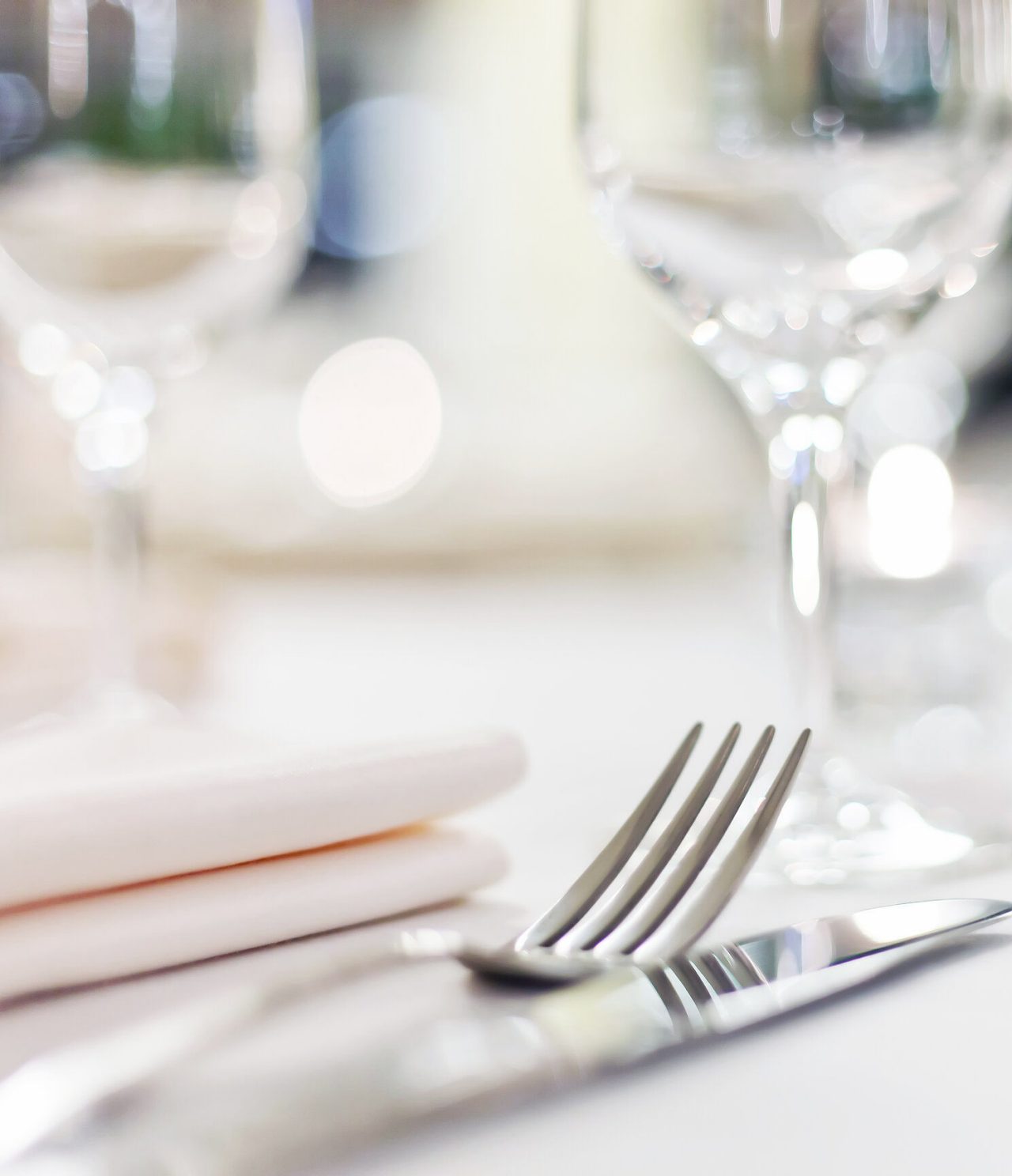 Discover Hotels in the Algarve featuring a softly lit dining table with wine glasses, folded napkins and cutlery
