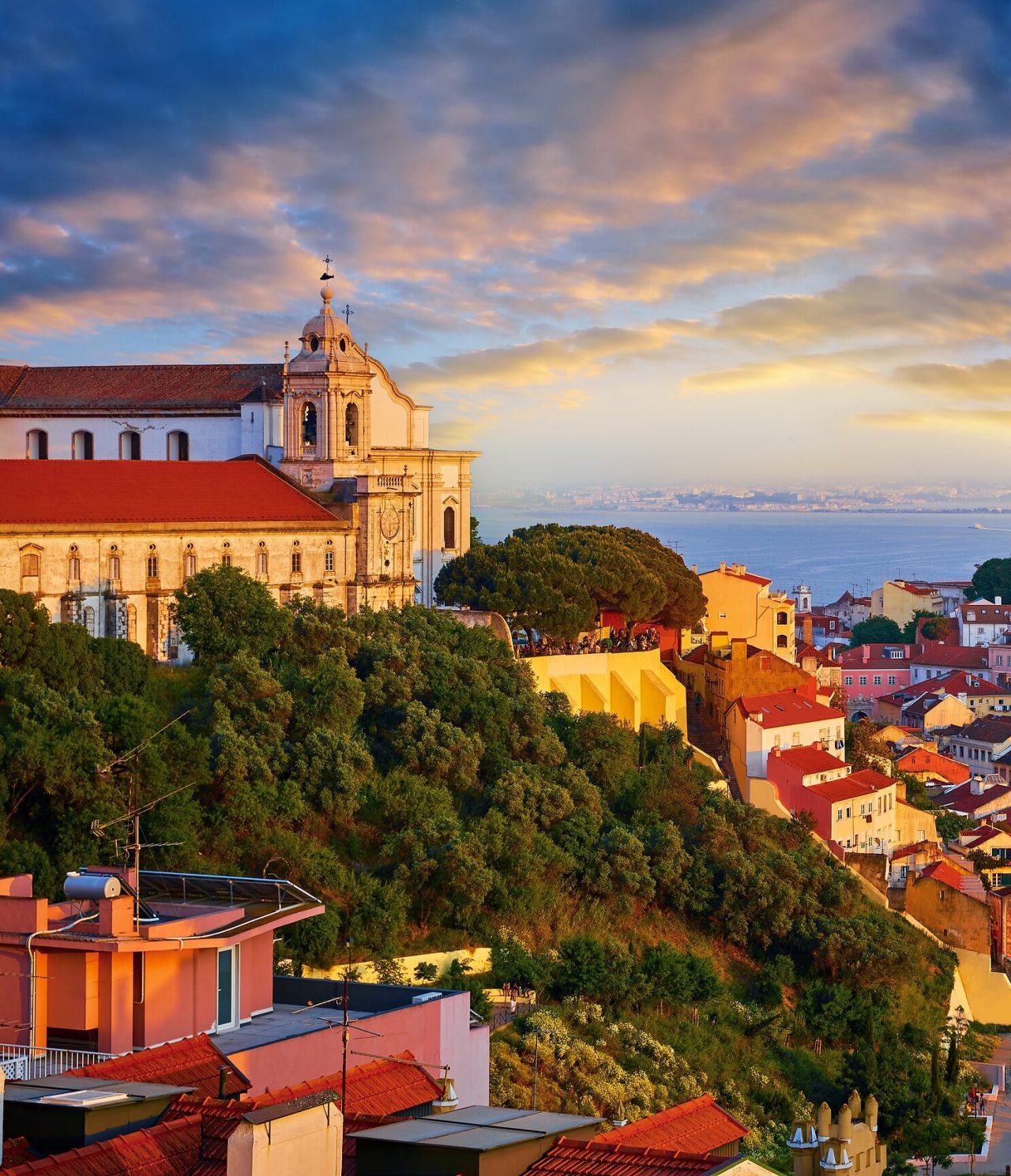 Vista aérea de una colina en Lisboa, con una iglesia en la cima, el río al fondo y la orilla sur del Tajo