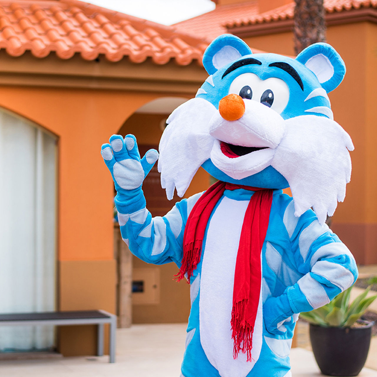 Pestaninha a rayas azules, mascota del Pestana Hotel Group, en un hotel todo incluido, con una bufanda roja