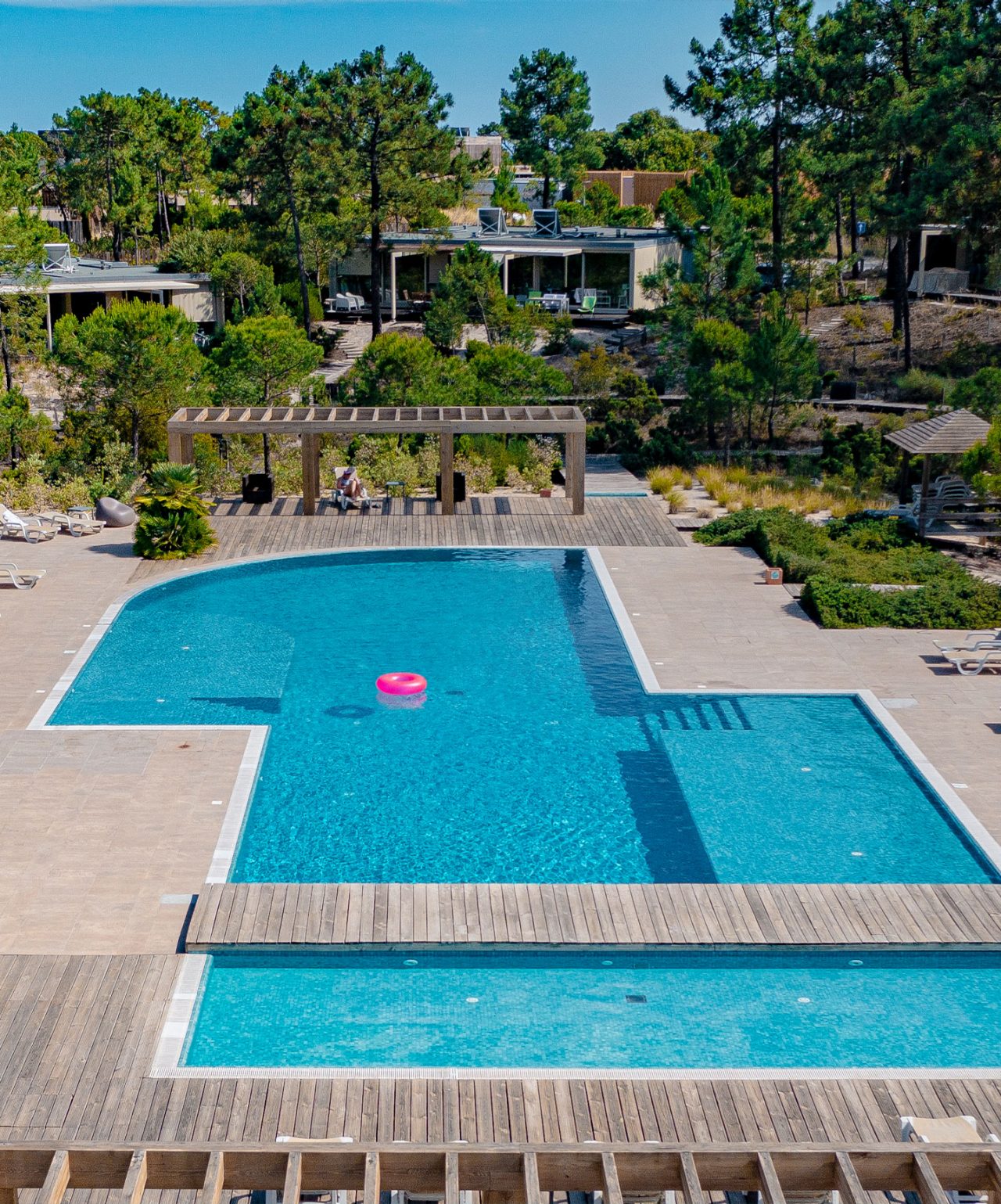 Piscina en Pestana Tróia, un Eco Resort en Alentejo, con un flotador rosa en el medio y naturaleza alrededor