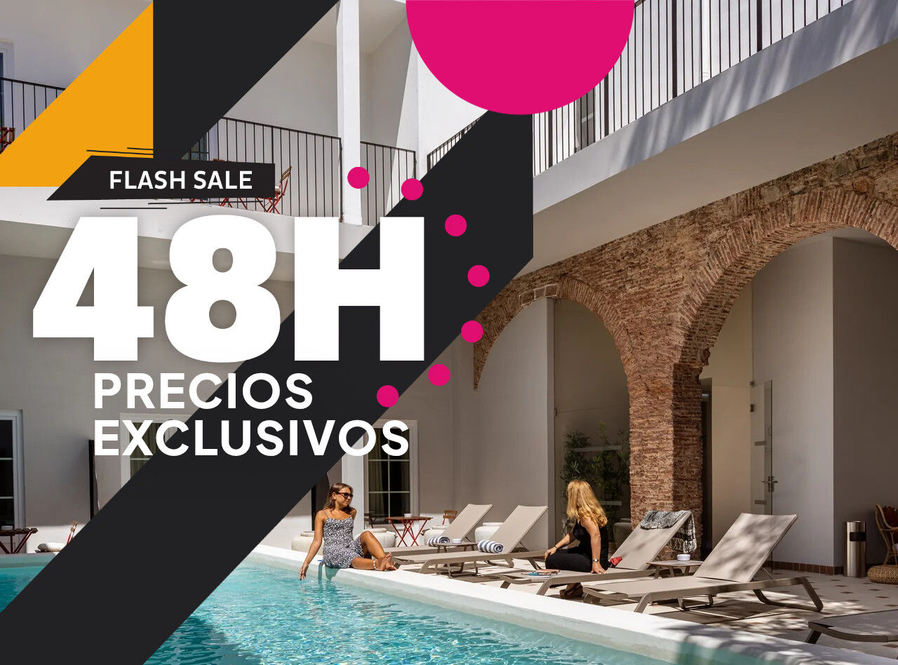 Patio interior con piscina, arcos de ladrillo y huéspedes descansando junto a reposeras bajo luz natural