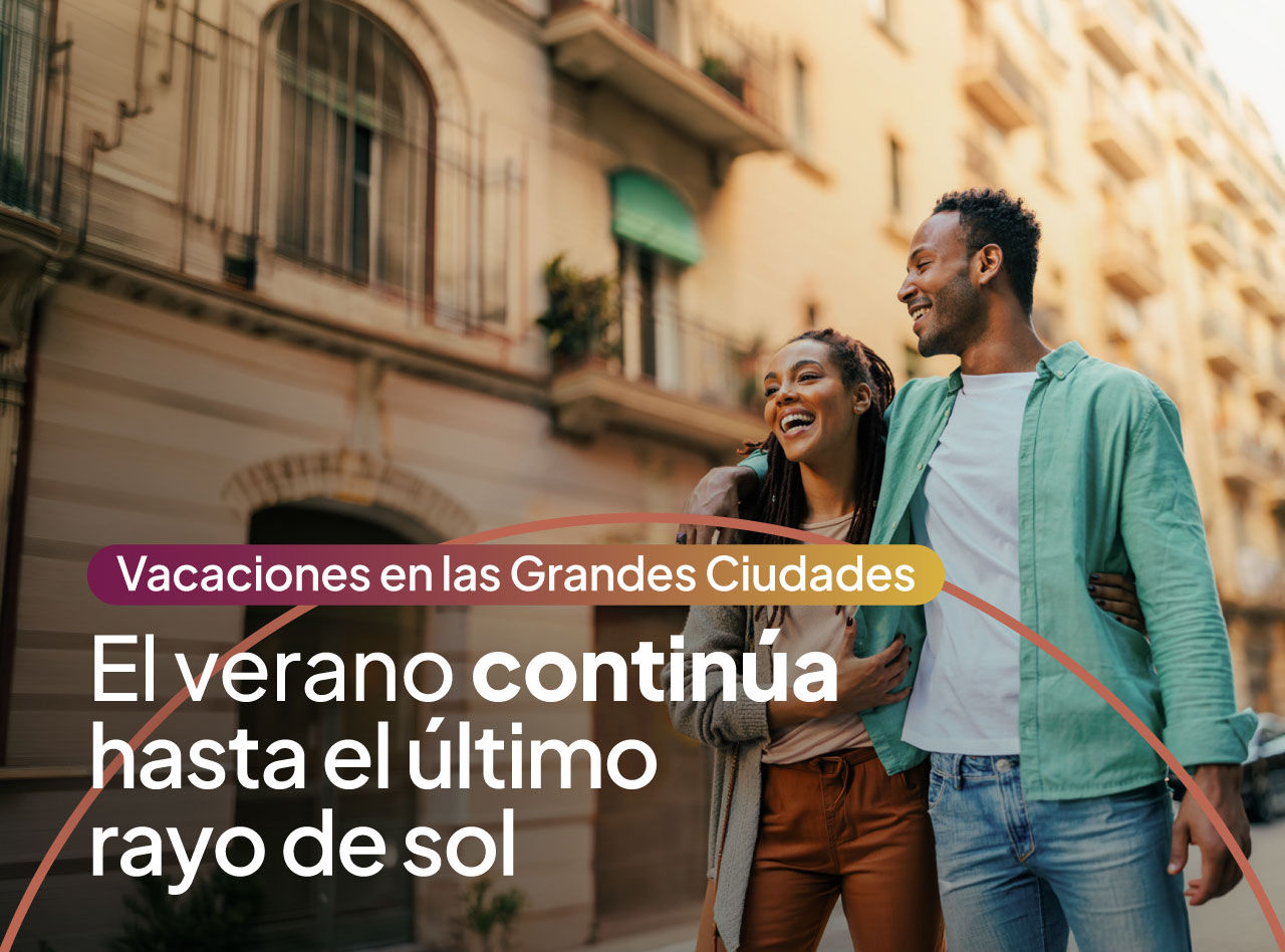 Pareja sonriente caminando abrazada por una calle urbana iluminada por el sol entre edificios residenciales