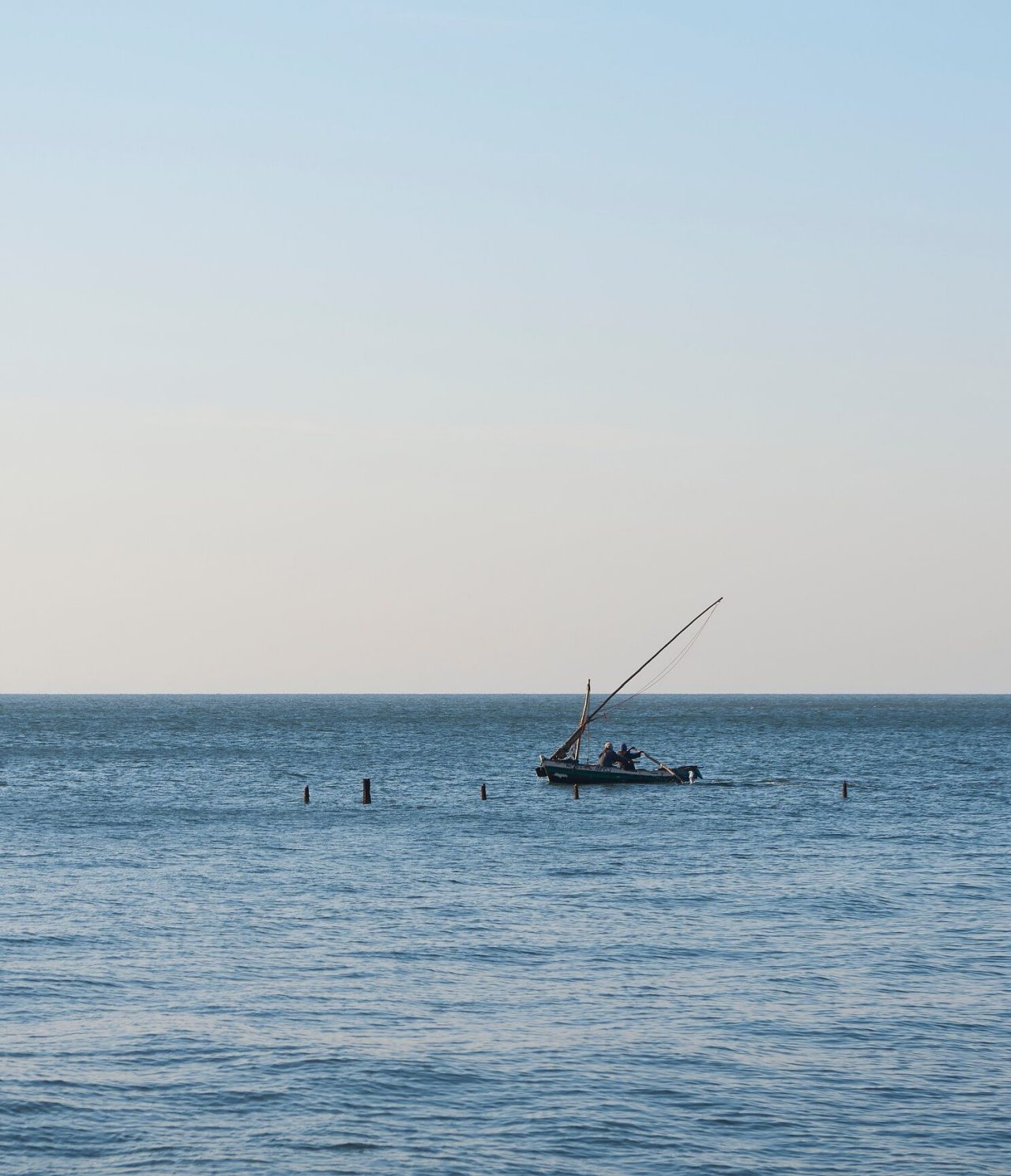 Mar alto onde uma pequena embarcação com dois homens está parada para pescar peixe