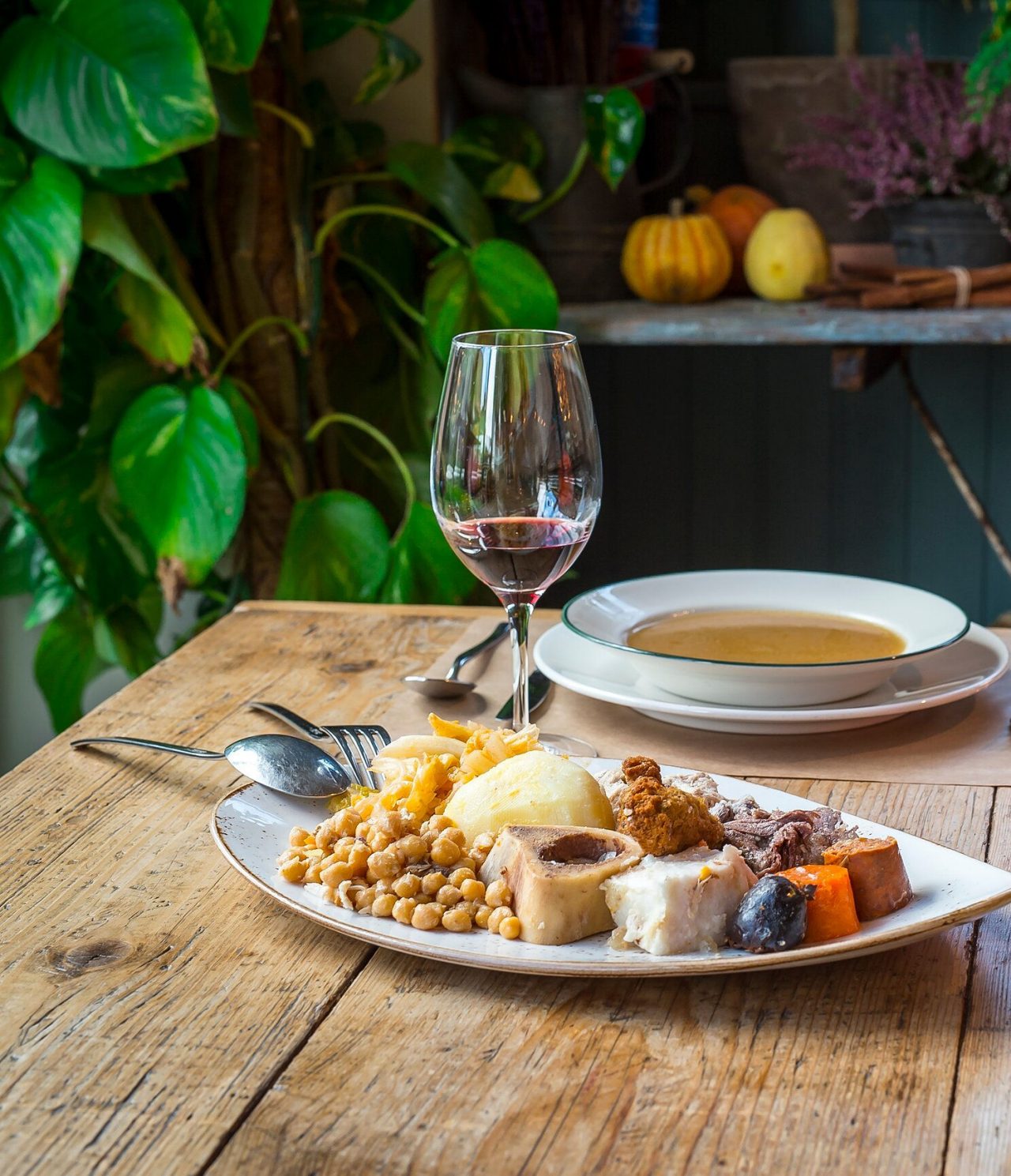 Mesa posta com um prato de sopa, uma travessa com comida típica de Madrid e um cesto de pão para acompanhar a refeição