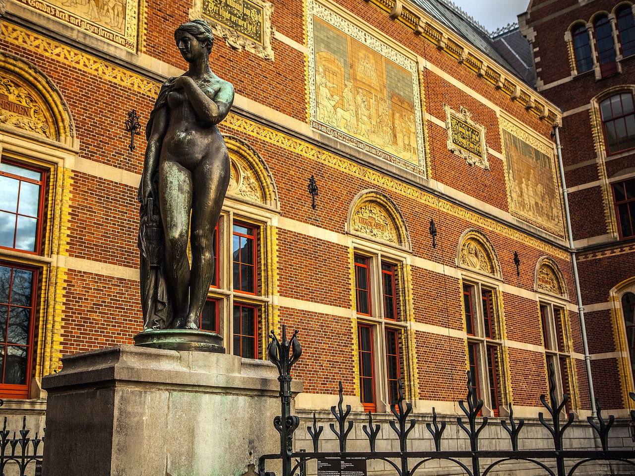 Estátua de uma mulher nua no Rijksmuseum, em frente a um edifício histórico em Amsterdão, na Holanda