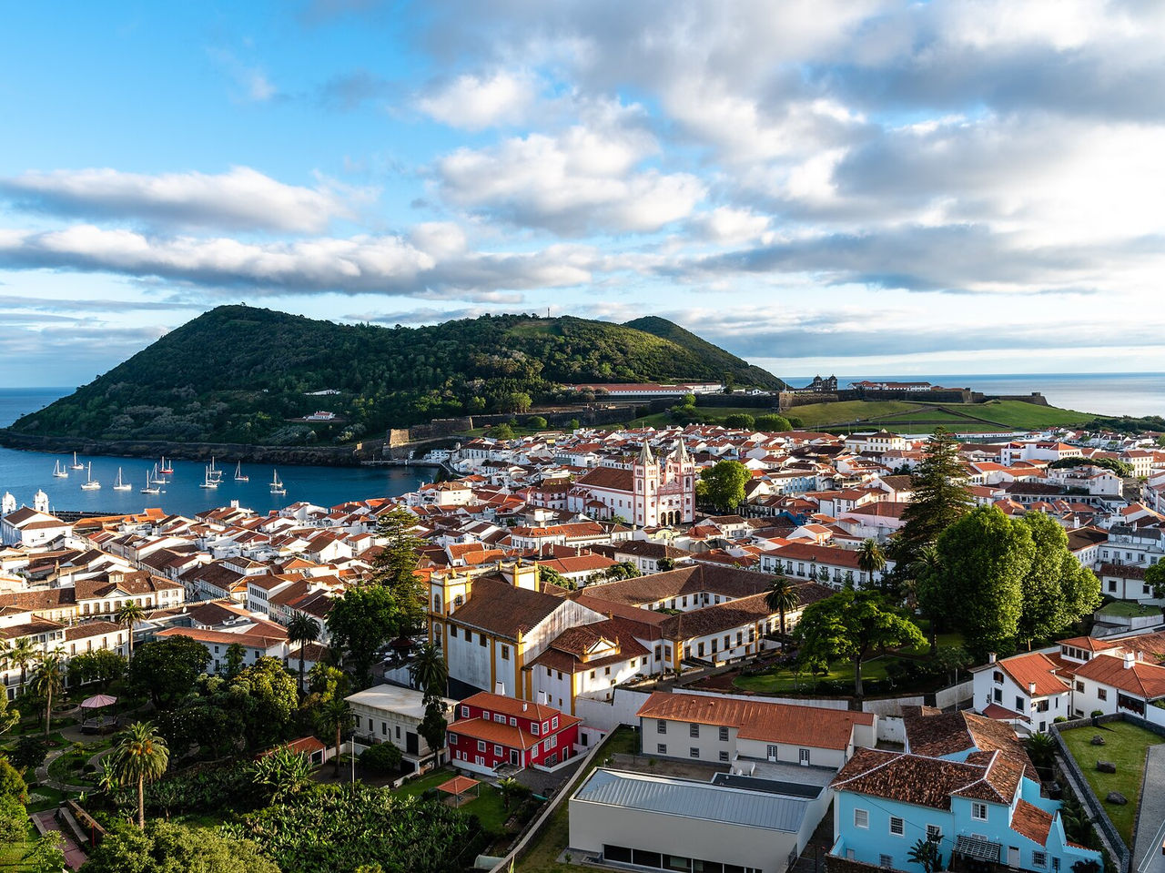 Vista panorâmica de Angra do Heroísmo, na Ilha Terceira, cercada por colinas verdes e pelo oceano Atlântico