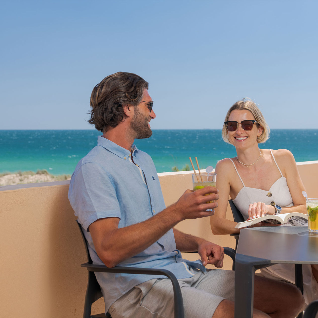 Casal bebe um sumo na varanda de uma villa privada no Pestana Alvor Beach Villas, com vista para o mar