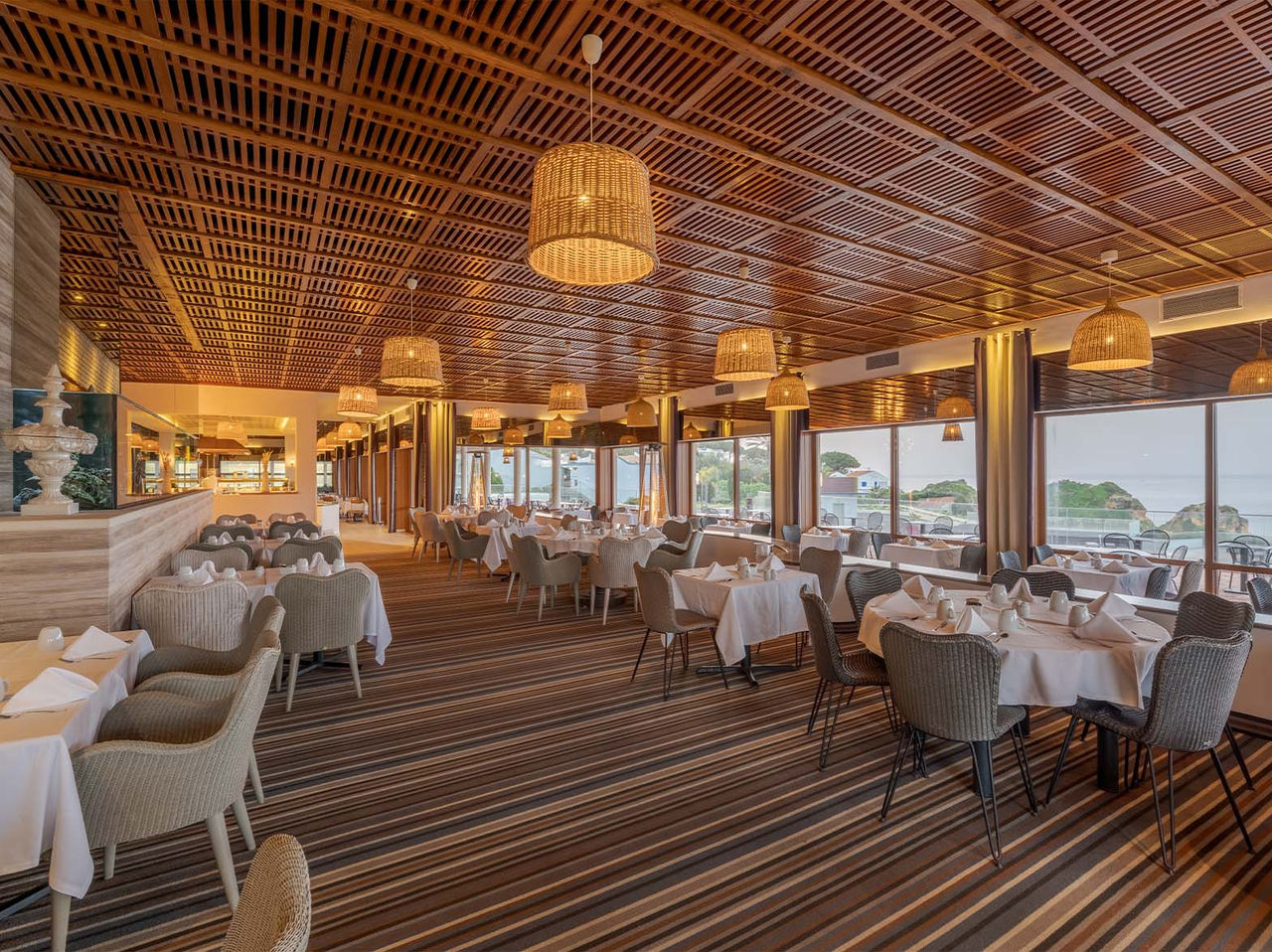 O restaurante Almofariz, do Hotel 5 Estrelas no Algarve, com ripas de madeira no teto, aquário e vista para o mar