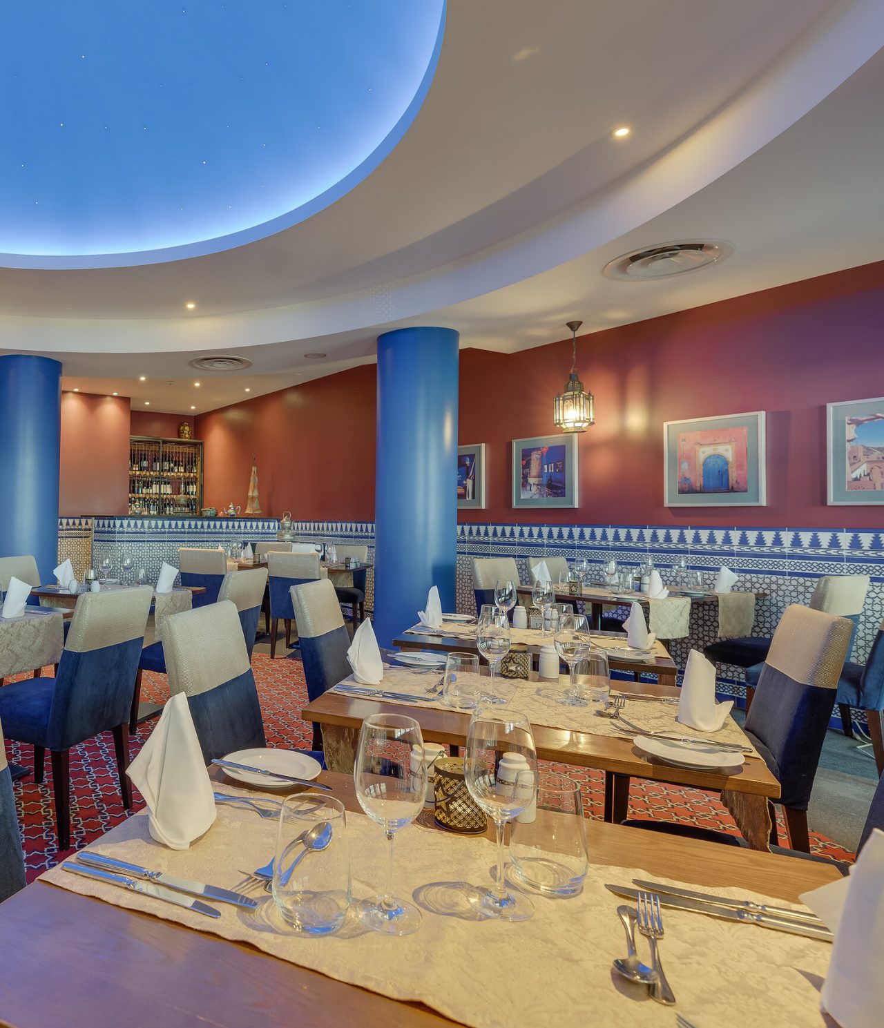 O restaurante Au Tagine, do Hotel 5 Estrelas no Funchal, na Madeira, tem uma sala ampla, com quadros, e mesas com cadeiras