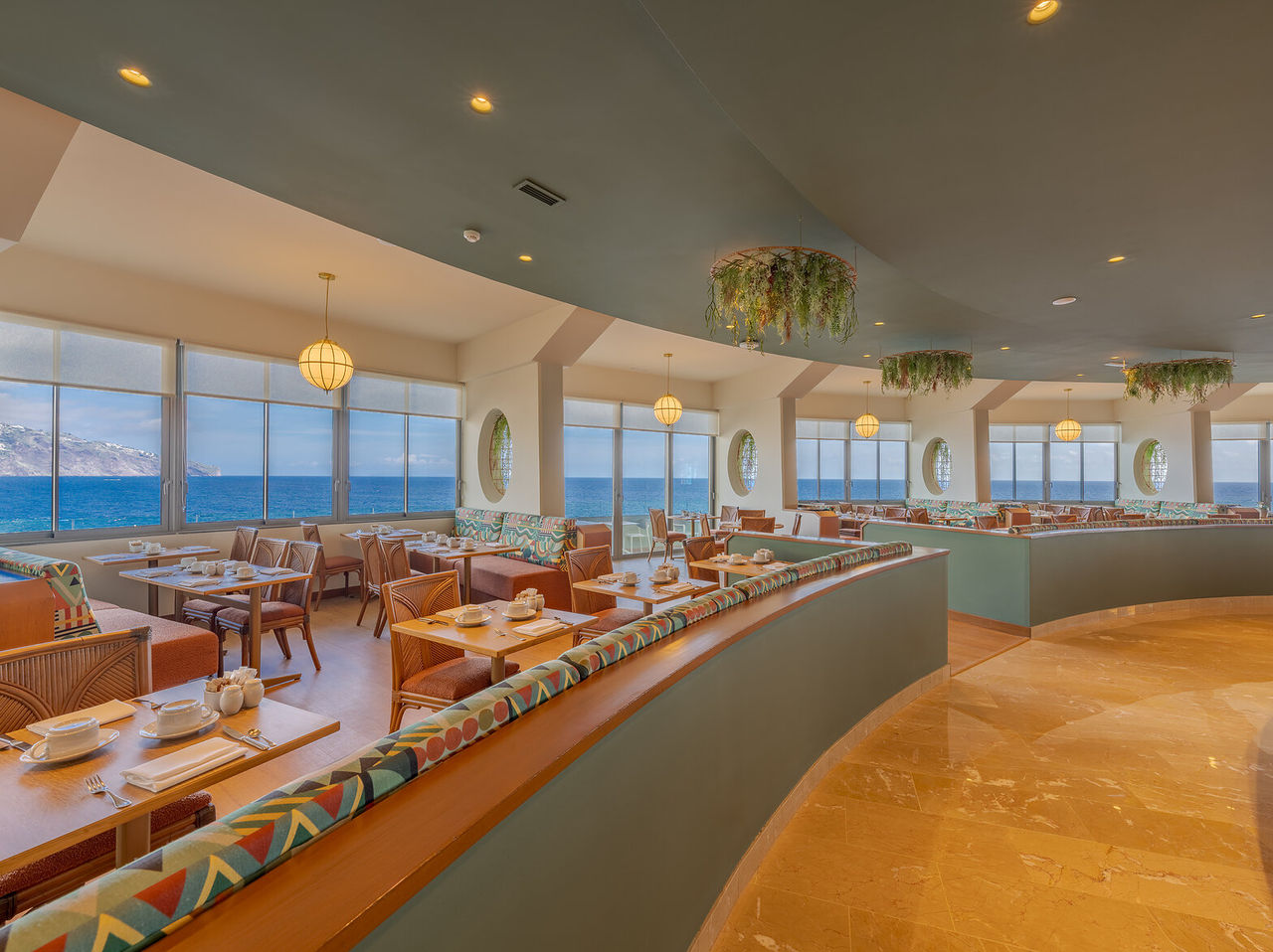 O restaurante Flor do Mar, do Hotel com Acesso ao Mar no Funchal, tem várias mesas com sofás, plantas e vista para o mar
