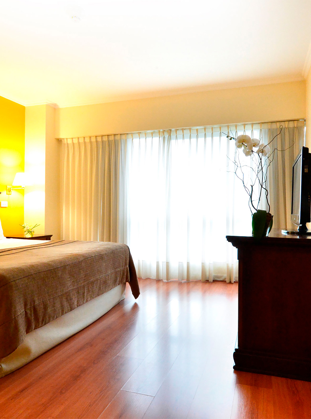 Das Queen Superior Zimmer im Pestana Buenos Aires hat ein Doppelbett, Fernseher, Spiegel und Nachttisch mit Lampe