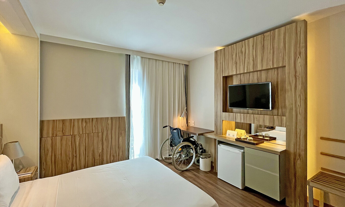 Das angepaste Zimmer hat ein Doppelbett und einen Schreibtisch mit einem Rollstuhl 