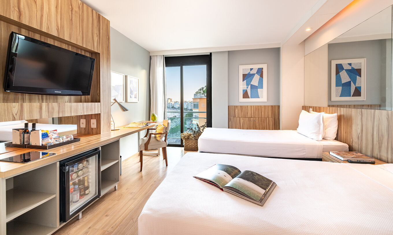 Das seitliche Meerblickzimmer hat zwei Betten, Fernseher und Fenster mit Blick auf den Strand von Copacabana 