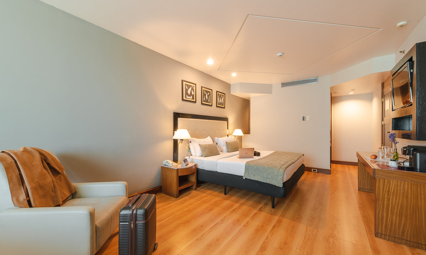 Die Executive Suite im Pestana São Paulo hat ein Schlafzimmer mit Doppelbett und Reisetasche