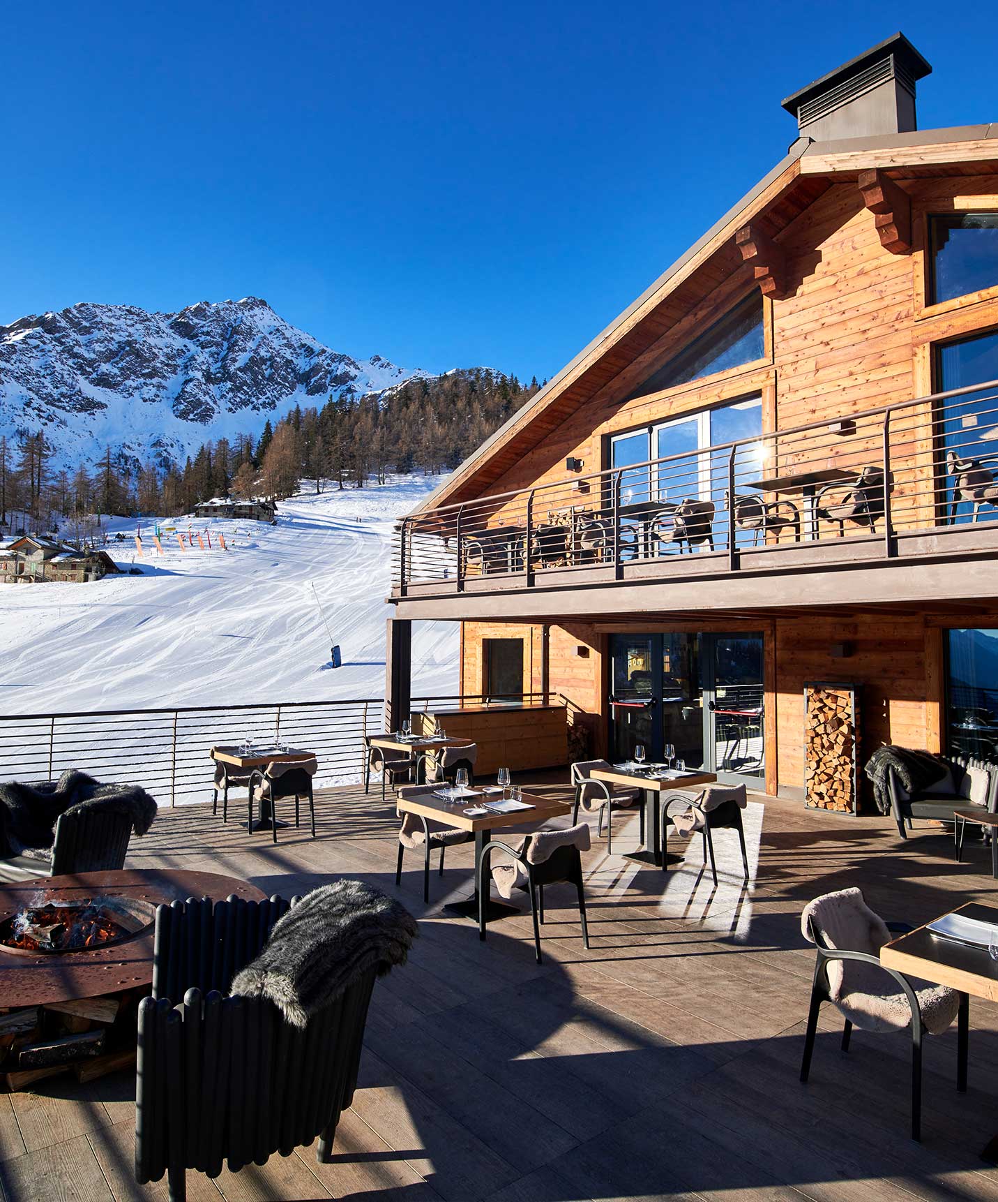 Le Massif Courmayeur, Hotel in den italienischen Alpen, Terrasse neben verschneiten Skipisten unter blauem Himmel