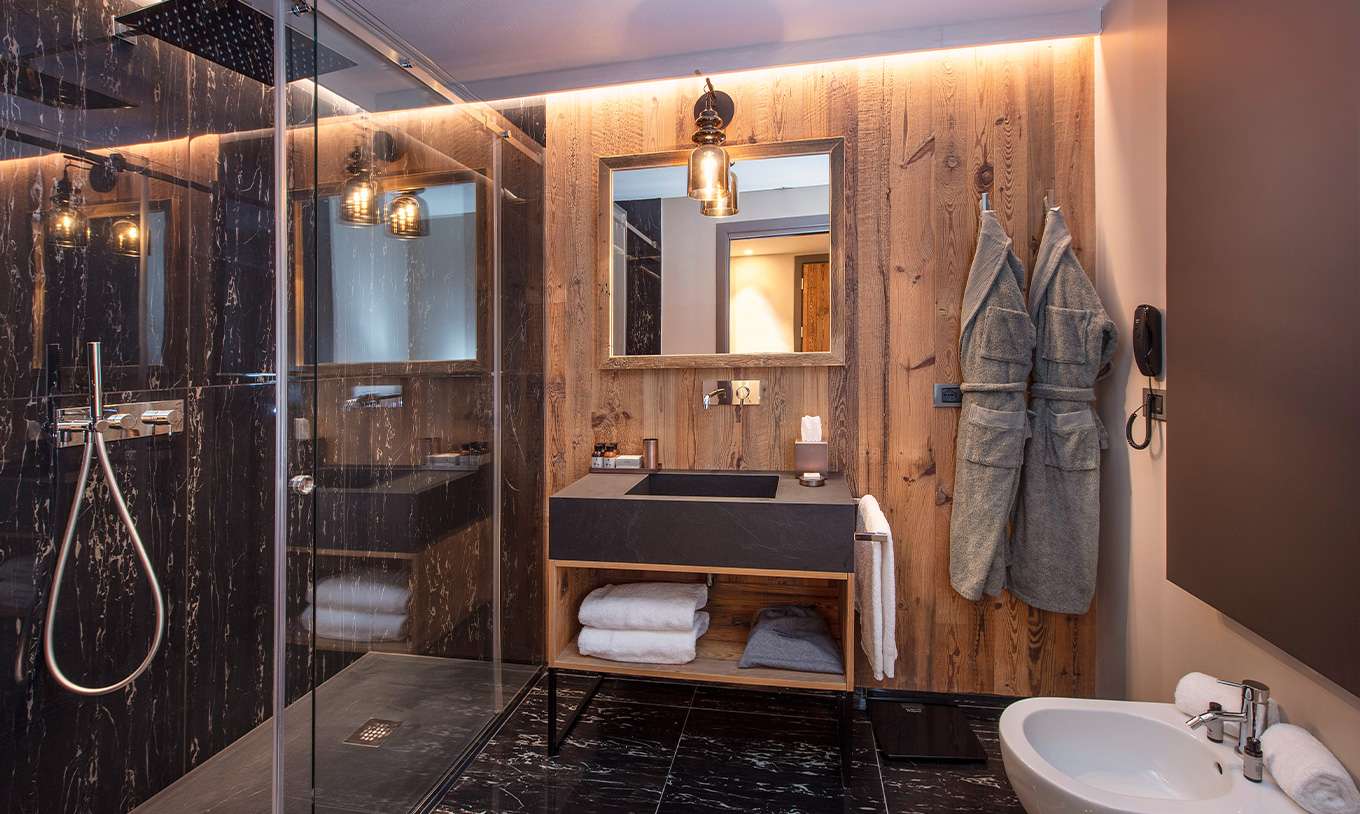 Familiensuite im Le Massif Courmayeur mit modernem Bad aus Holz, Glasdusche, Waschbecken und Bademänteln