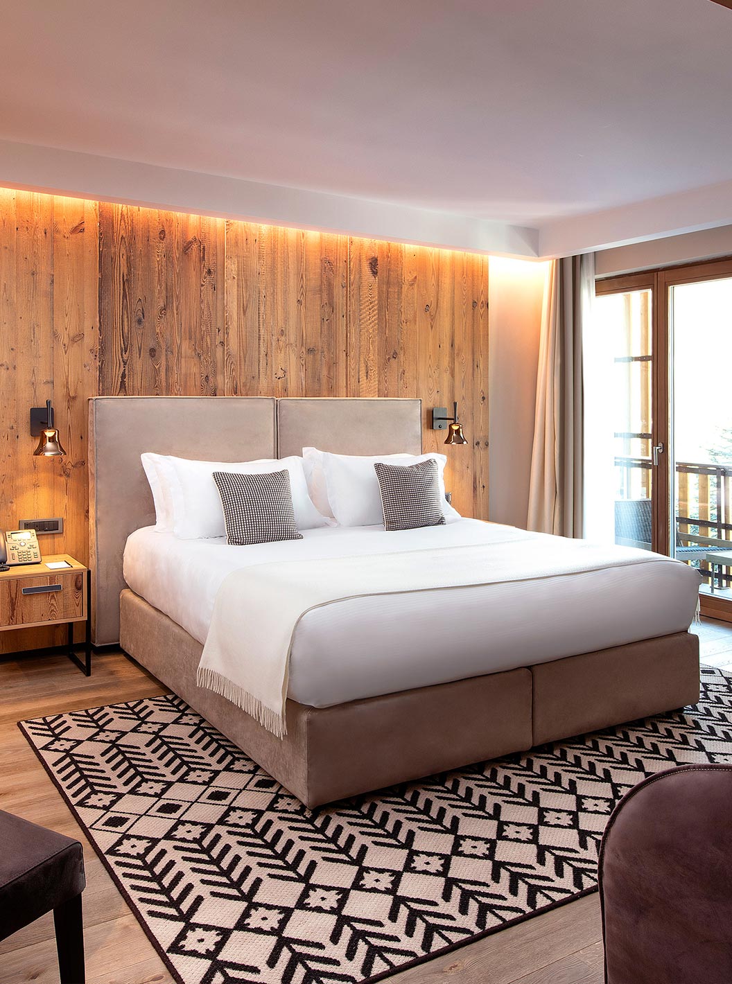Junior Suite im Le Massif Courmayeur mit großem Doppelbett, Holzwänden, Sitzbereich und Balkonfenster