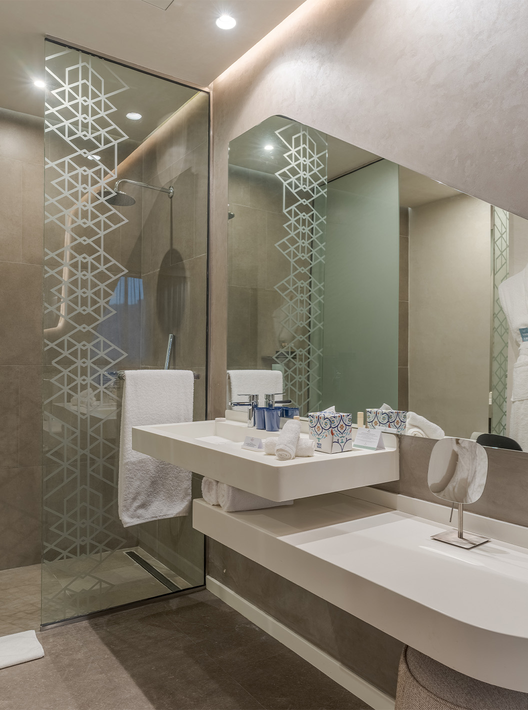Die CR7 Junior Suite Avenue im Pestana CR7 Marrakeck hat ein Bad mit Waschbecken, Spiegel und begehbarer Dusche