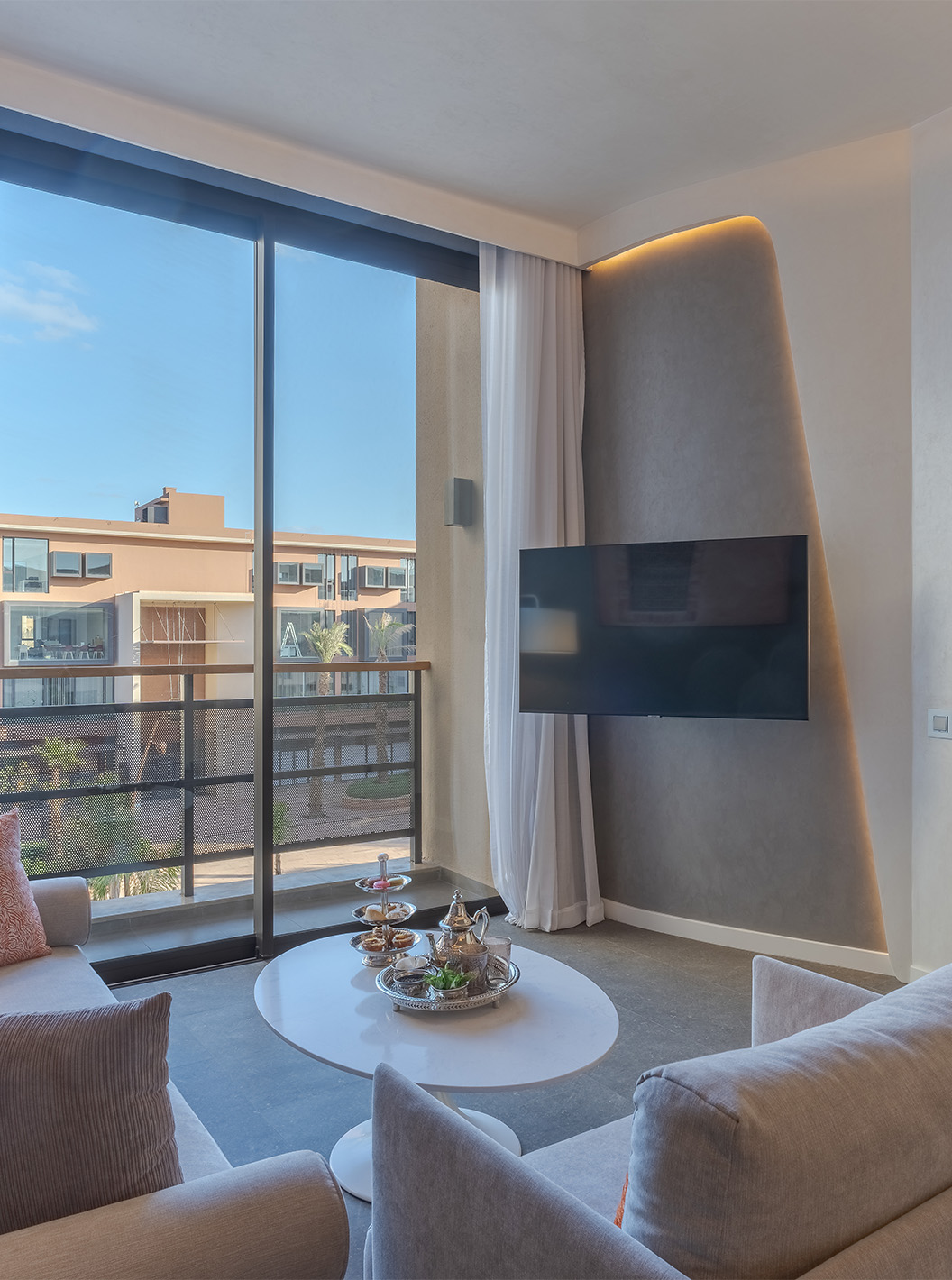 Die CR7 Suite Avenue im Pestana CR7 Marrakeck hat ein Wohnzimmer mit Sofas, Fernseher und Balkon mit Blick auf die M Avenue