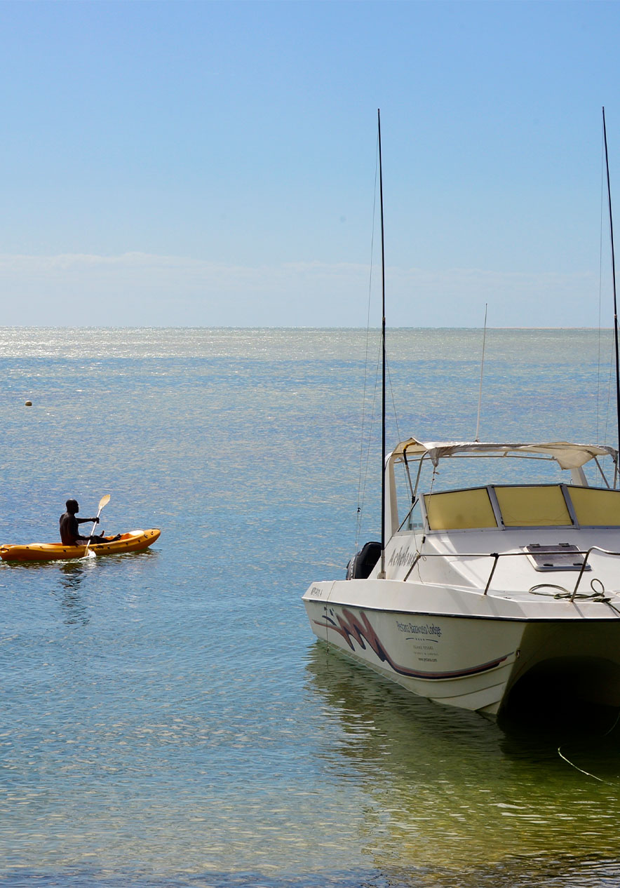 Kajaktour nahe Pestana Bazaruto Lodge, Eco Resort na Ilha de Bazaruto, mit ruhigem Meer und Booten im Sonnenlicht