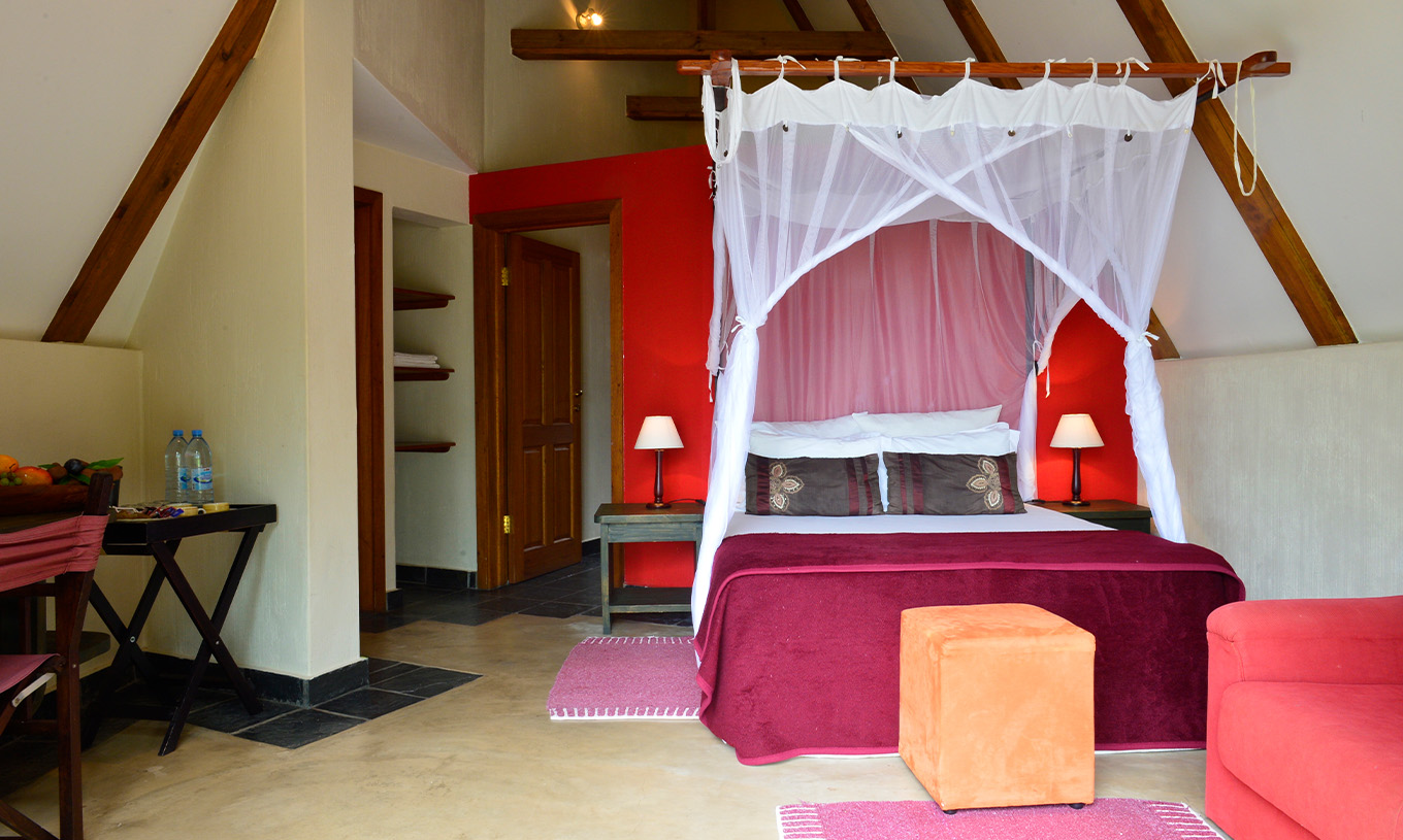 Der Bungalow T1 im Pestana Bazaruto Lodge hat eine rote Dekoration mit Doppelbett, Sofa und Schreibtisch
