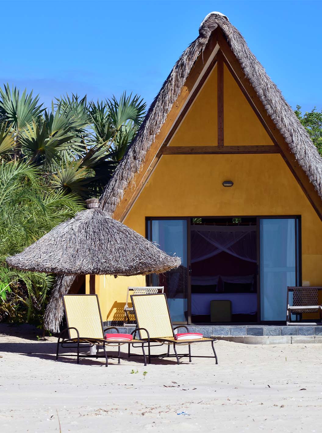Der Bungalow T1 im Pestana Bazaruto Lodge ist ein gelbes Häuschen am Strand mit einem Strohdach in A-Form