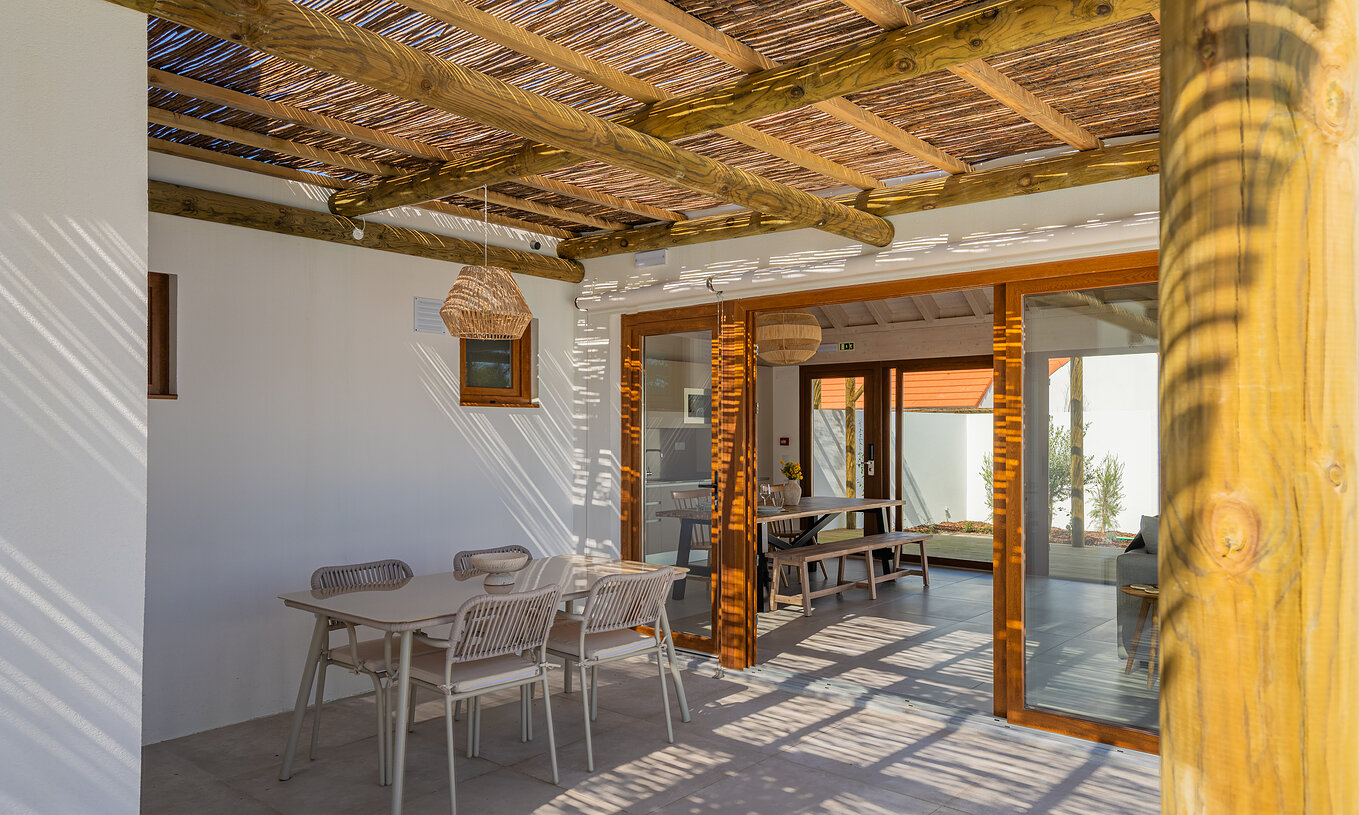 Die Premium Villa im Pestana Comporta Village Residences hat eine überdachte Terrasse mit Tisch, der ins Innere führt