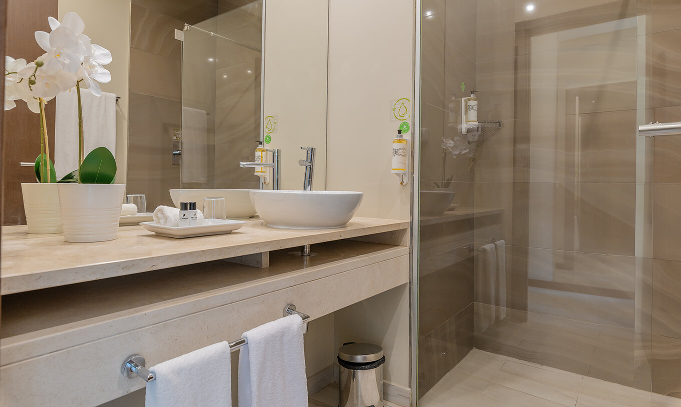 Die Garden Suite im Pestana Alvor Park hat ein Badezimmer mit Badewanne und Waschbecken mit einer Blumenvase
