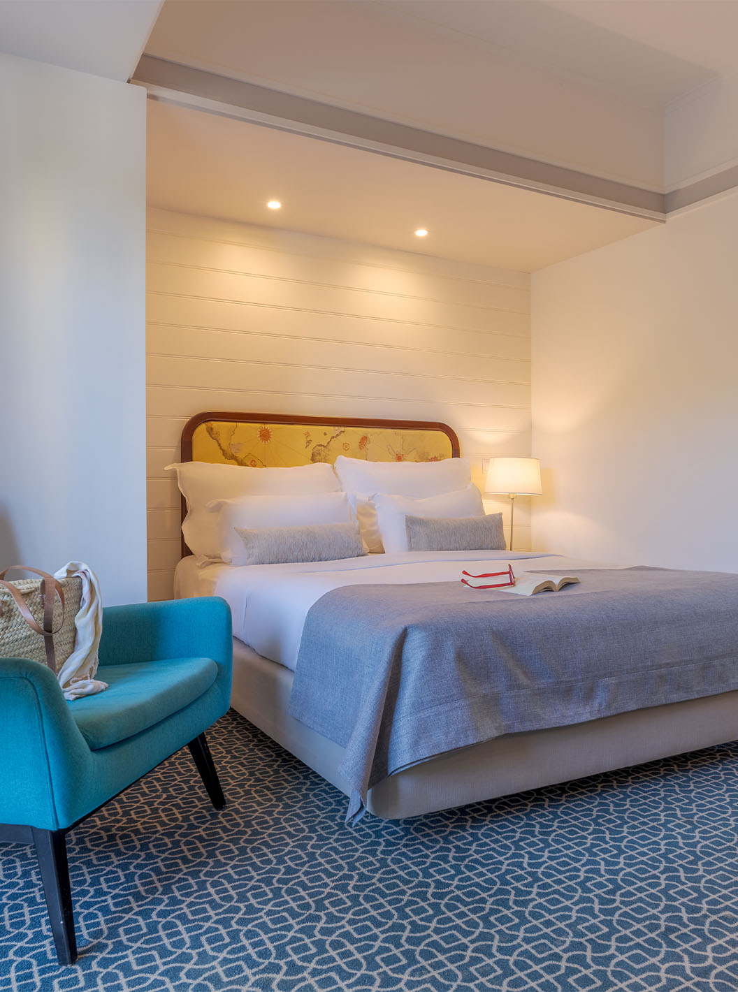 Das Deluxe im Pestana Alvor Praia hat ein Doppelbett, einen Tisch mit einem blauen Sessel und einen Spiegel