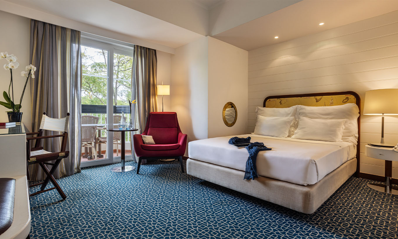 Die Suite mit Gartenblick im Pestana Alvor Praia hat ein Doppelbett, einen roten Sessel und einen Balkon mit Gartenblick