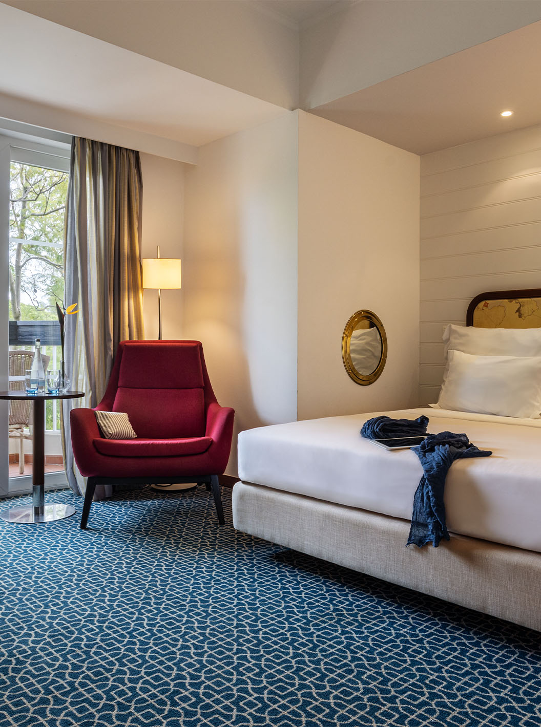 Die Suite mit Gartenblick im Pestana Alvor Praia hat ein Doppelbett, einen roten Sessel und einen Balkon mit Gartenblick