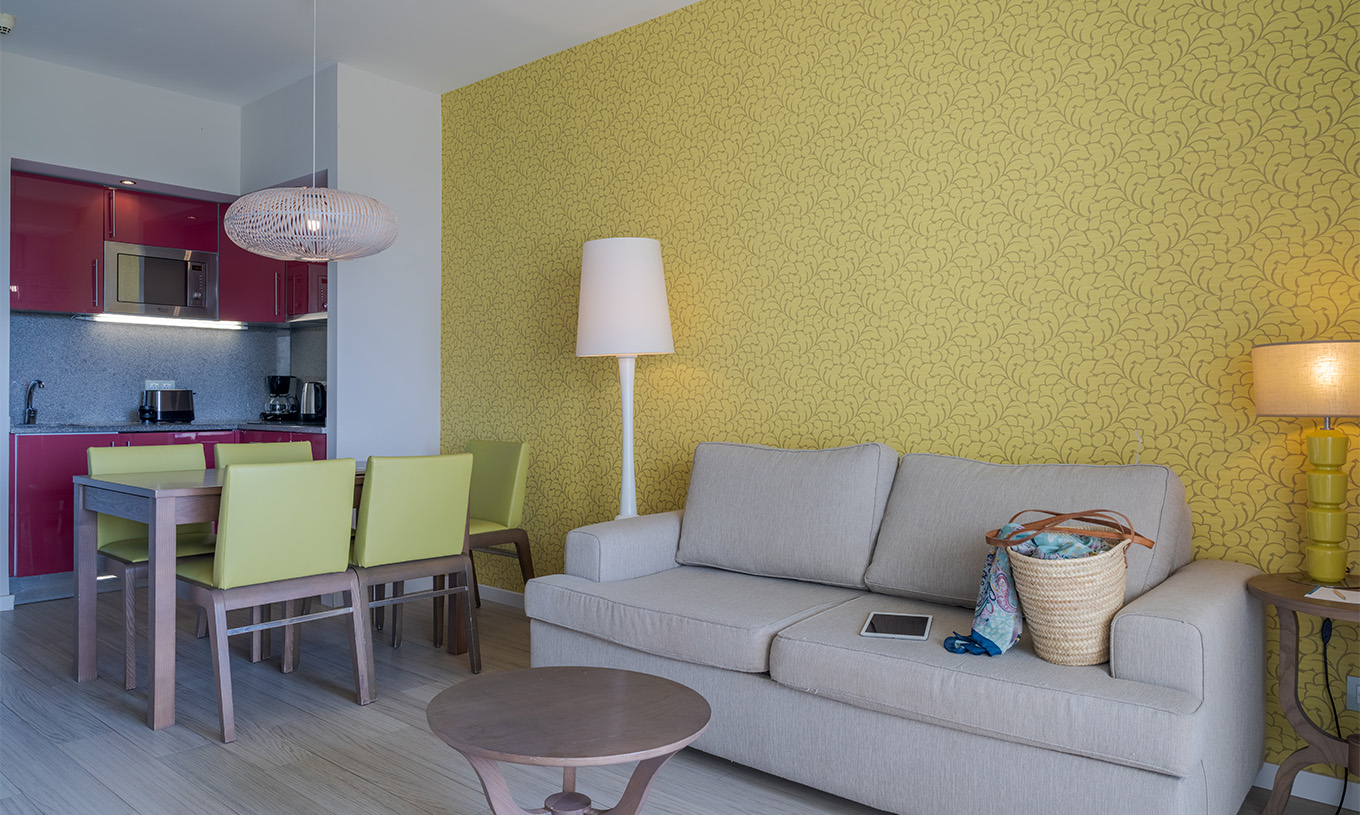 Die Suite T1 mit Gartenblick im Pestana Alvor Praia hat einen Esstisch mit fünf grünen Stühlen und ein Sofa mit Tisch