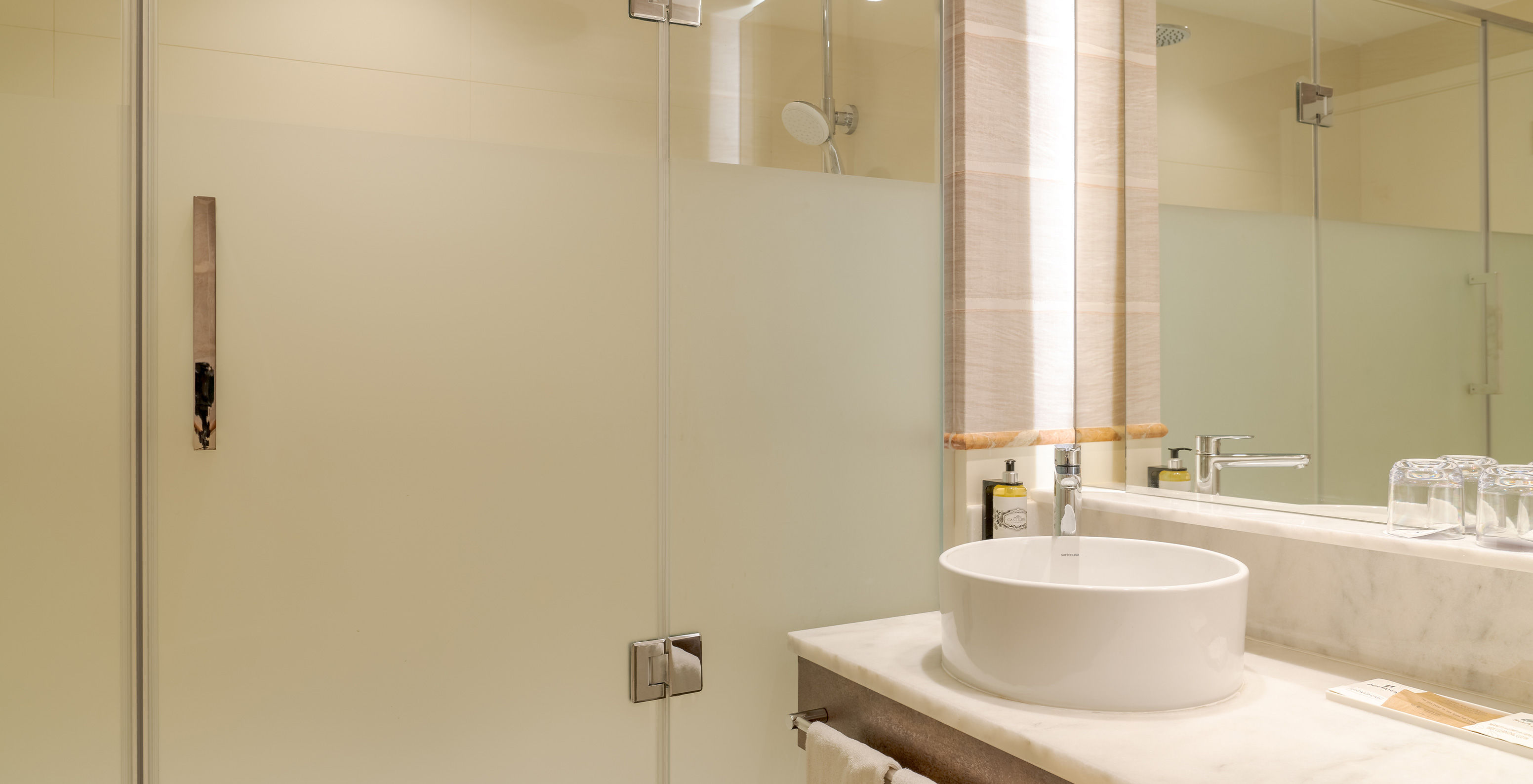 Das Familienzimmer im Pestana Blue Alvor Beach hat ein Bad mit Waschbecken, Spiegel, Handtüchern und Dusche