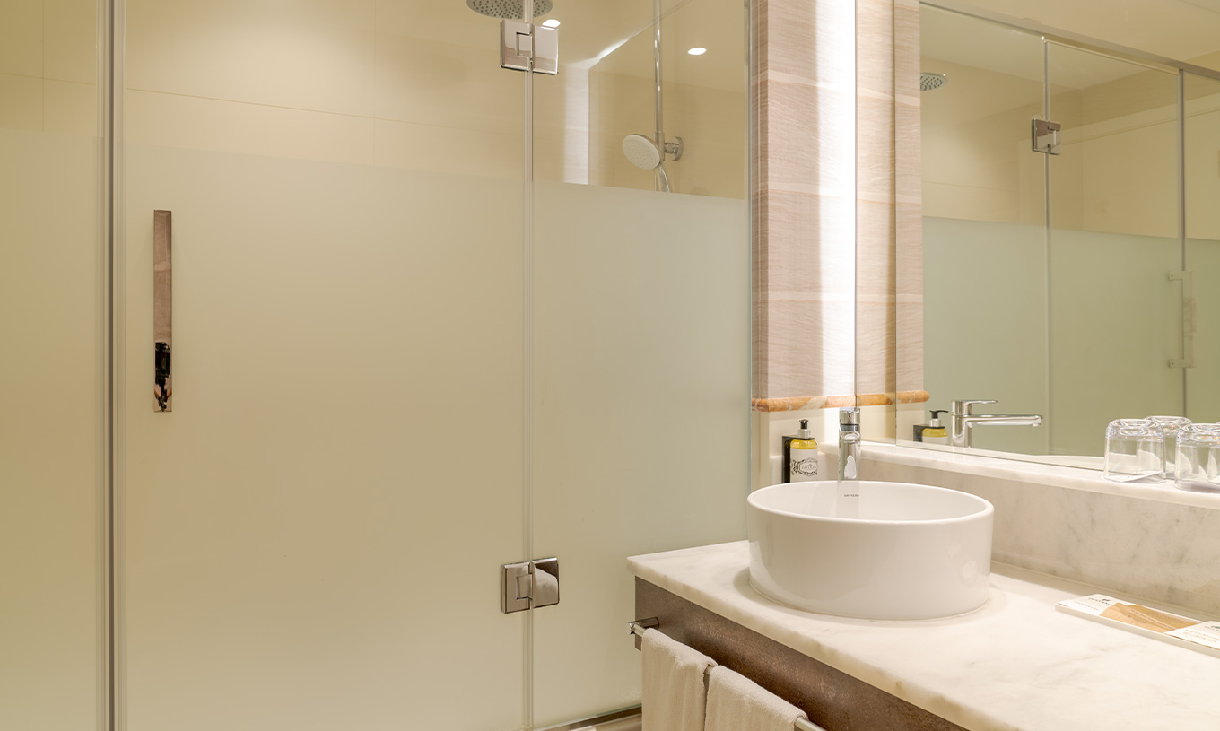 Das Familienzimmer im Pestana Blue Alvor Beach hat ein Bad mit Waschbecken, Spiegel, Handtüchern und Dusche