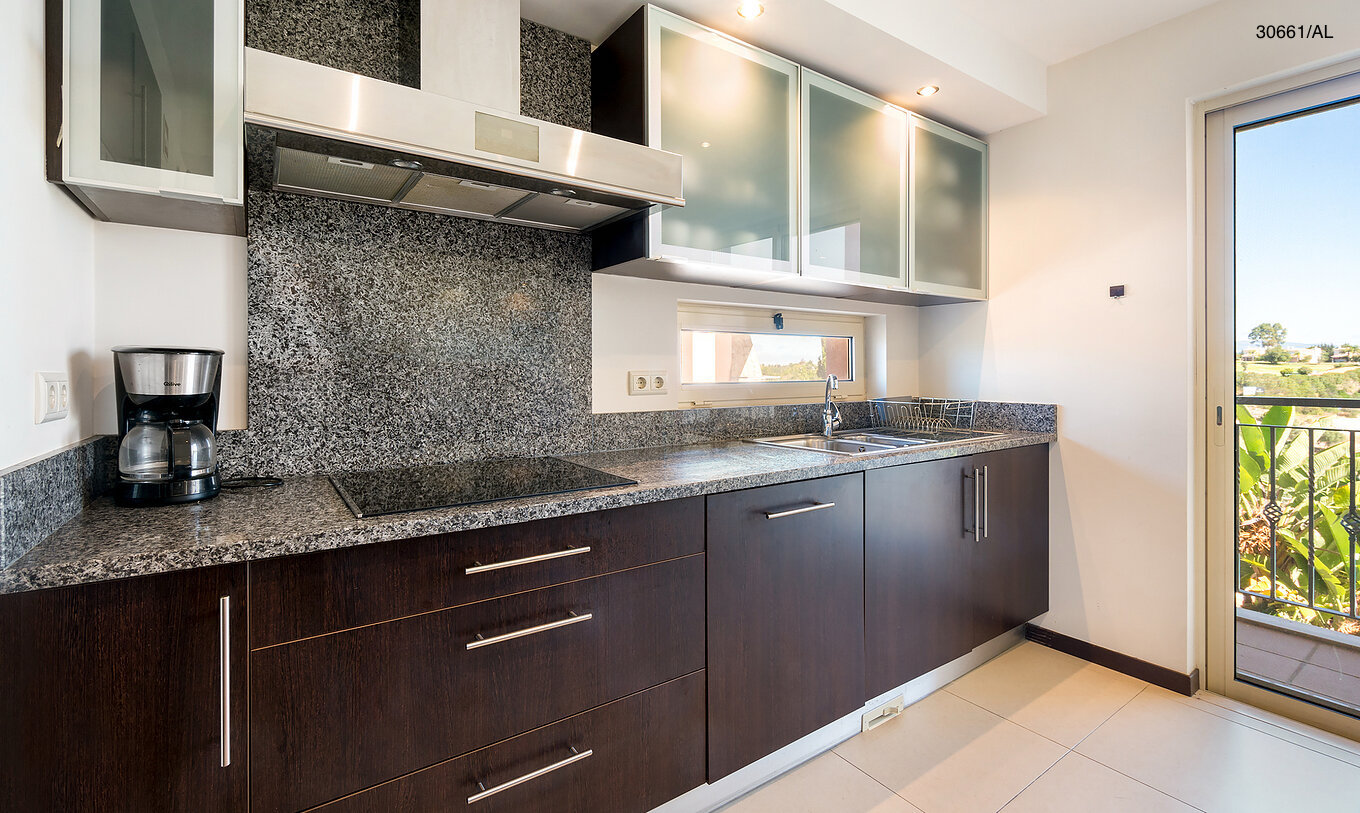 Die Wohnung Pestana Carvoeiro Golf T1 Superior hat eine Küche mit dunklen Holzschränken und Granitarbeitsplatte