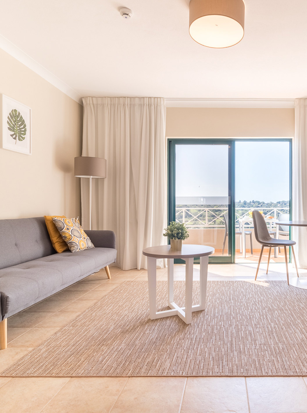 Das Studio im Pestana Gramacho Residences hat ein Wohnzimmer mit grauem Sofa, TV, Tisch und hellem Balkon