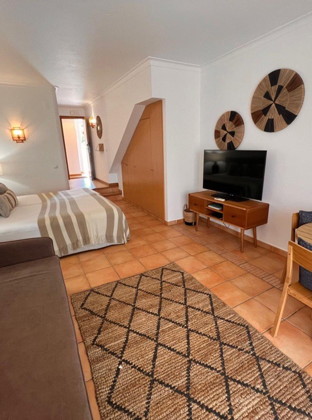 Studio im Pestana Palm Gardens mit Doppelbett, Holztisch, Sofa und Fernseher in hellem Wohnbereich