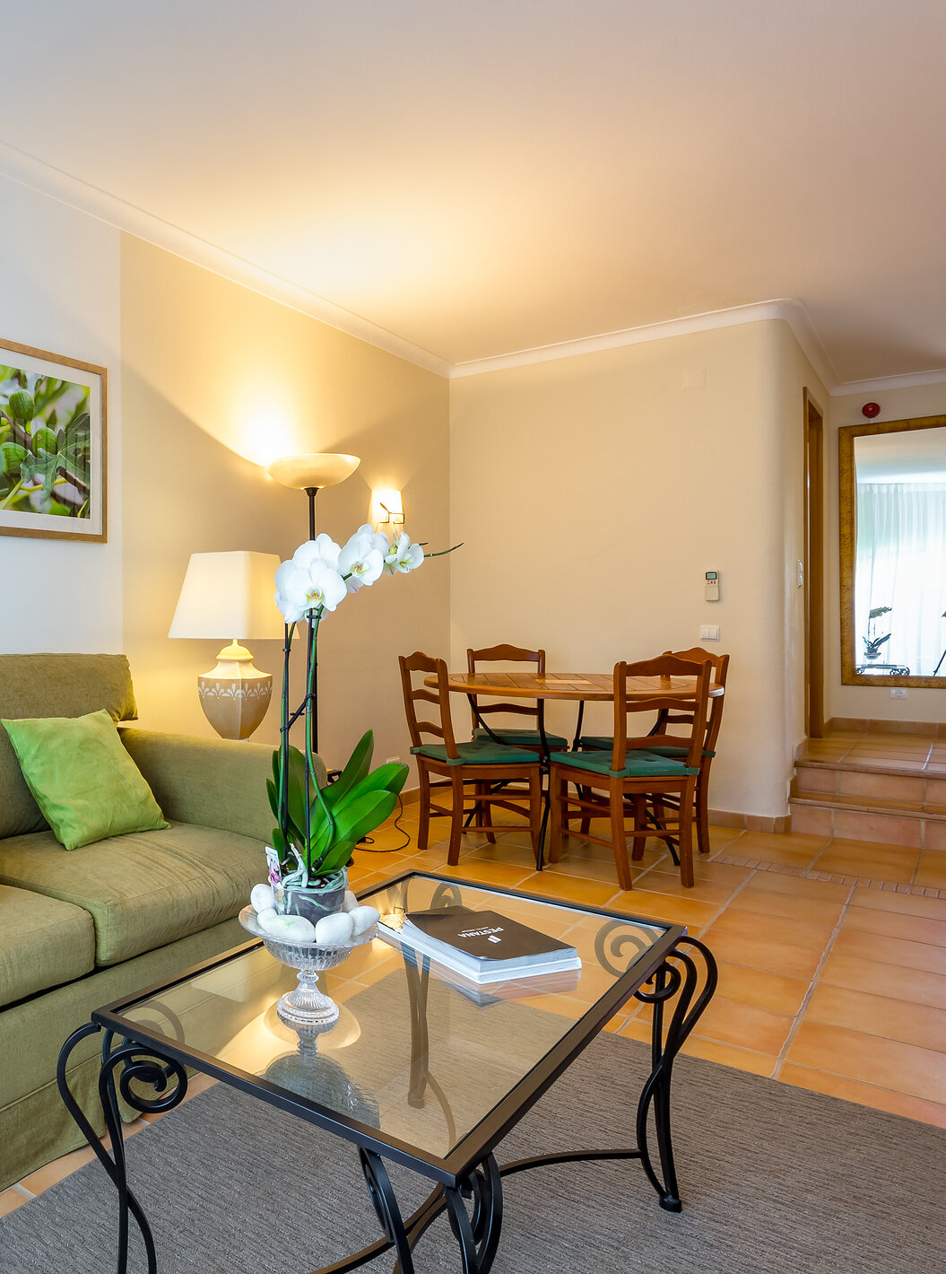 Das T2 Standard Appartement im Pestana Palm Gardens hat ein Wohnzimmer mit Sofa, Kissen, einem runden Tisch und Bildern