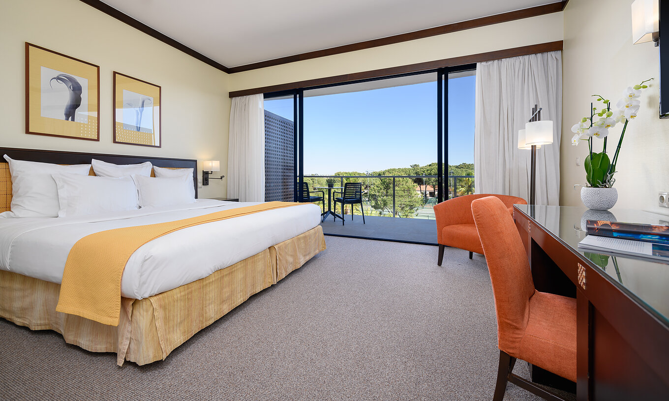 Superior Pestana Vila Sol - Vilamoura hat ein Doppelbett, einen Schreibtisch, Sessel und einen Balkon mit Stühlen