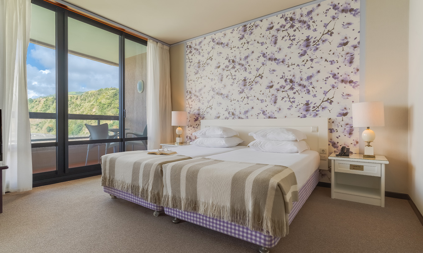 In der Junior Suite mit Meerblick im Pestana Bahia Praia stehen die Betten neben dem Balkon mit Blick auf die Gärten