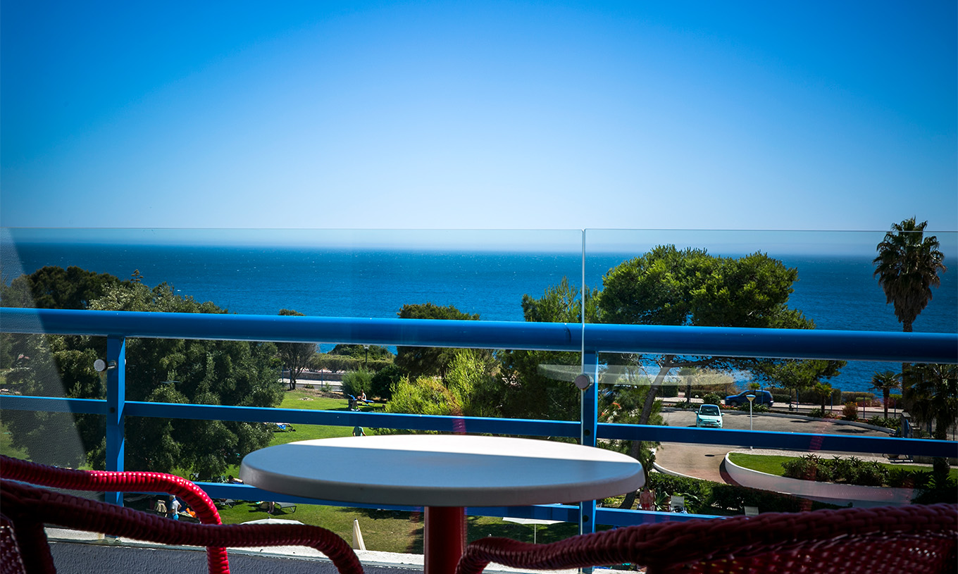 Das Deluxe-Zimmer mit Meerblick im Pestana Cascais hat einen Balkon mit Tisch und Stühlen mit Blick auf das Meer