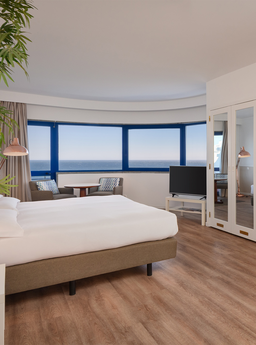 Das Deluxe Superior-Zimmer mit Meerblick im Pestana Cascais hat ein Doppelbett, TV, Spiegel und Blick auf das Meer
