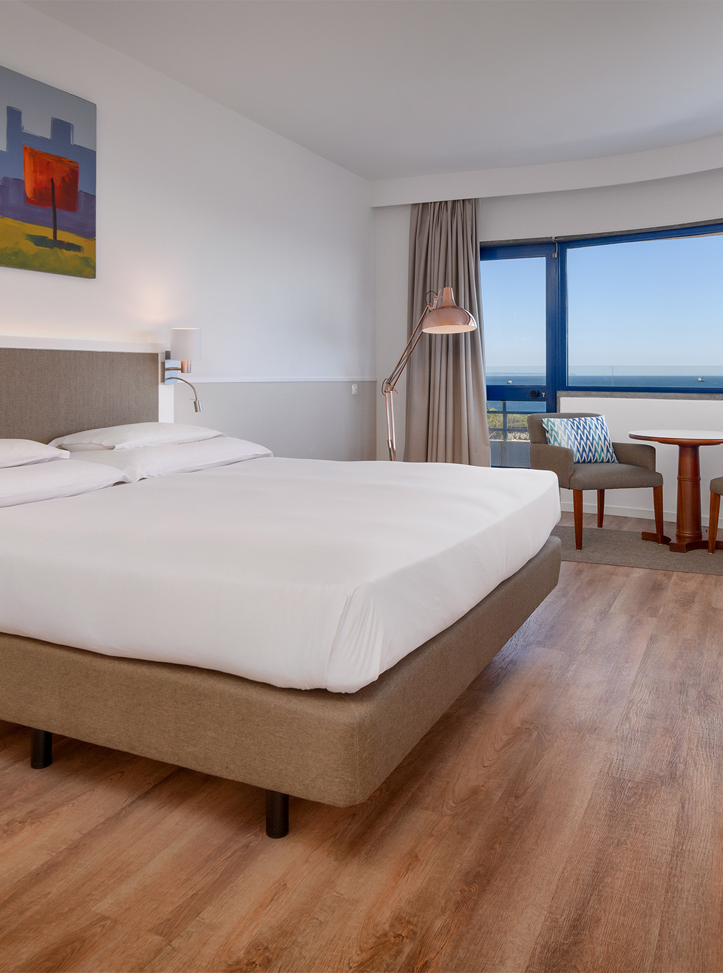 Die Deluxe Suite mit Meerblick im Pestana Cascais hat ein Doppelbett, TV und ein Bild an der Wand