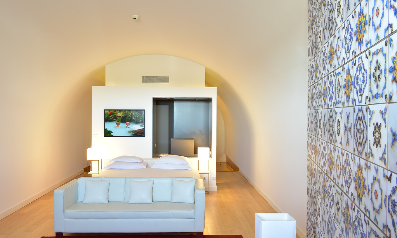 Die Junior Suite Art District im Pestana Cidadela Cascais hat ein Doppelbett, ein weißes Sofa und ein Bild an der Wand