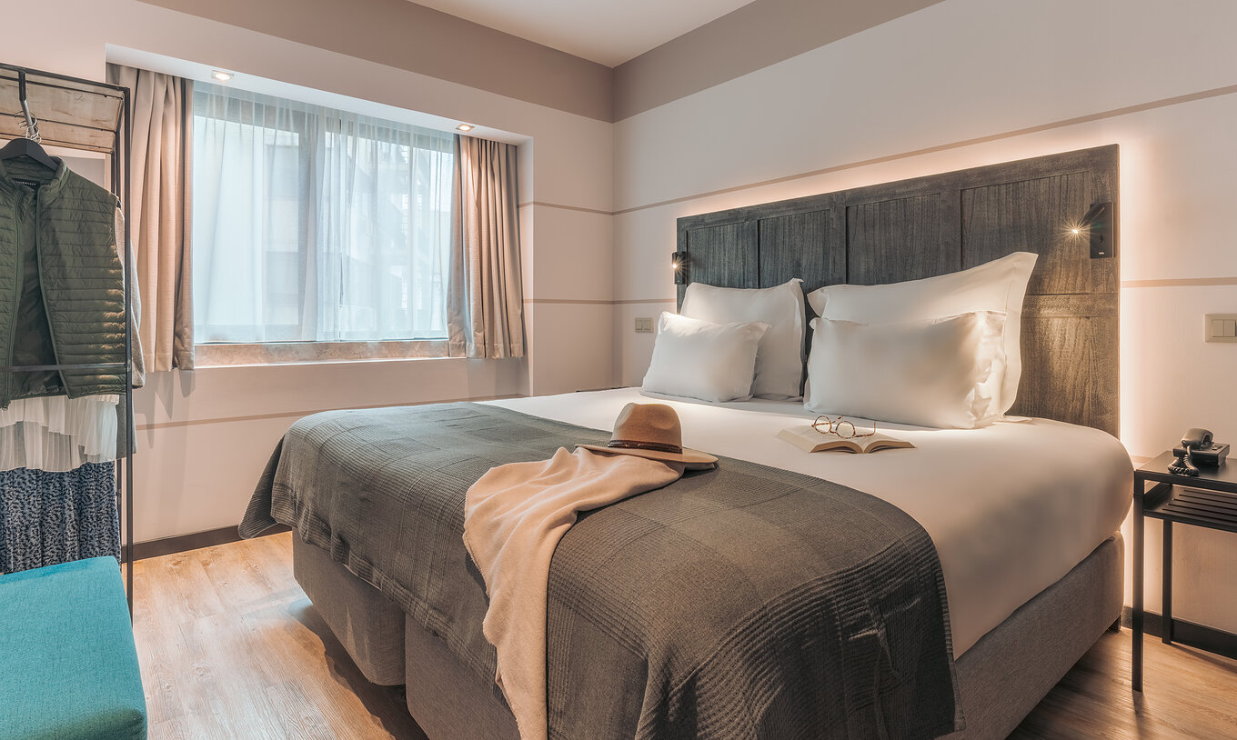 Die Junior Suite im Pestana Lisboa Vintage hat Doppelbett mit Decke, blauen Sofa, Nachttisch und Schrank