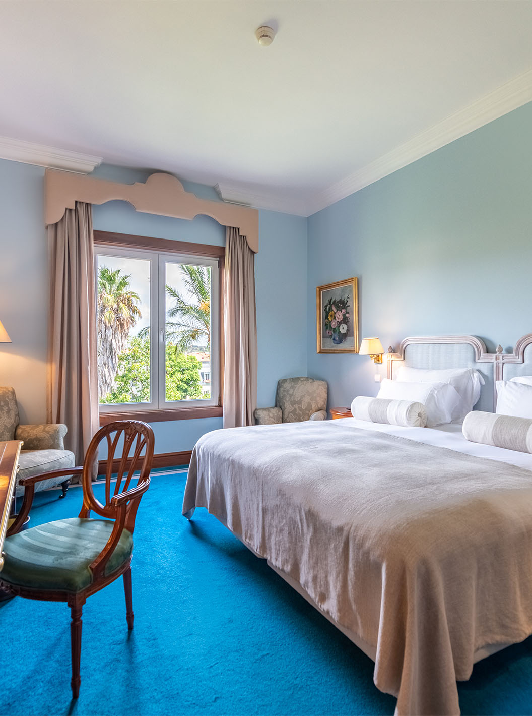 Das Deluxe Garden Zimmer im Pestana Palace Lisboa hat ein Doppelbett, zwei Nachttische und ein Fenster mit Gartenblick