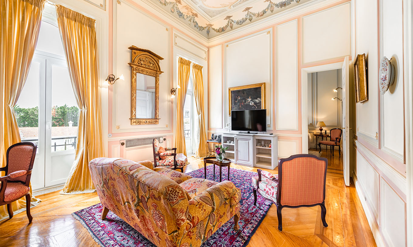 Die D. Amélia Suite im Pestana Palace Lisboa hat ein Wohnzimmer mit Sofa, Fernseher und zwei große Fenster