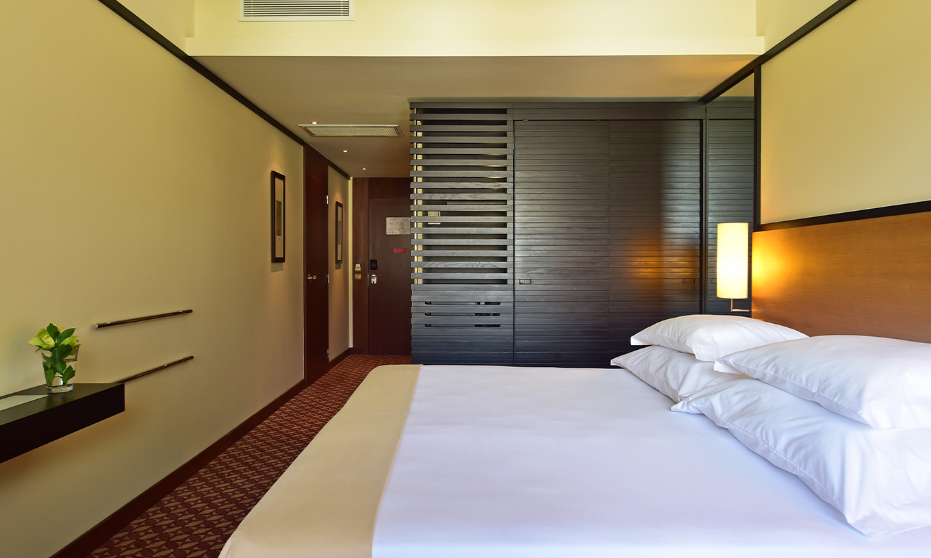 Das Familienzimmer im Pestana Casino Park hat ein Doppelbett mit einem dunklen Holzschrank daneben und einer Lampe